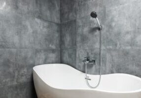 Bathroom interior with bathtub under shower on tile wall